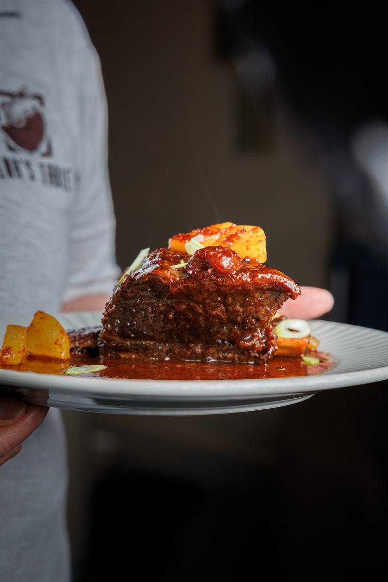 A plate of braised beef finished with sauce, presented in the dining room