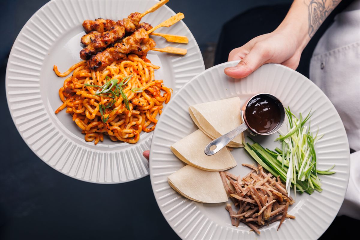 Overhead spread of grilled skewers, noodles and dipping sauces