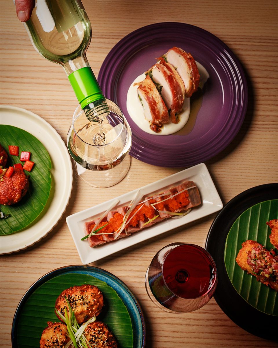 Overhead sharing table of Filipino, Malaysian and Japanese dishes with wine