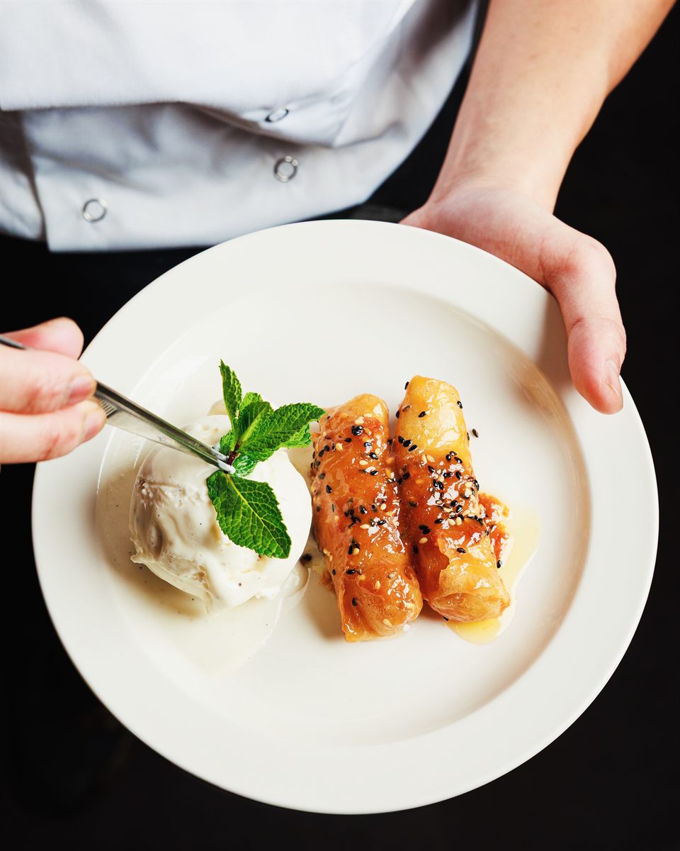 Banana spring rolls with ice cream and mint, presented by a chef