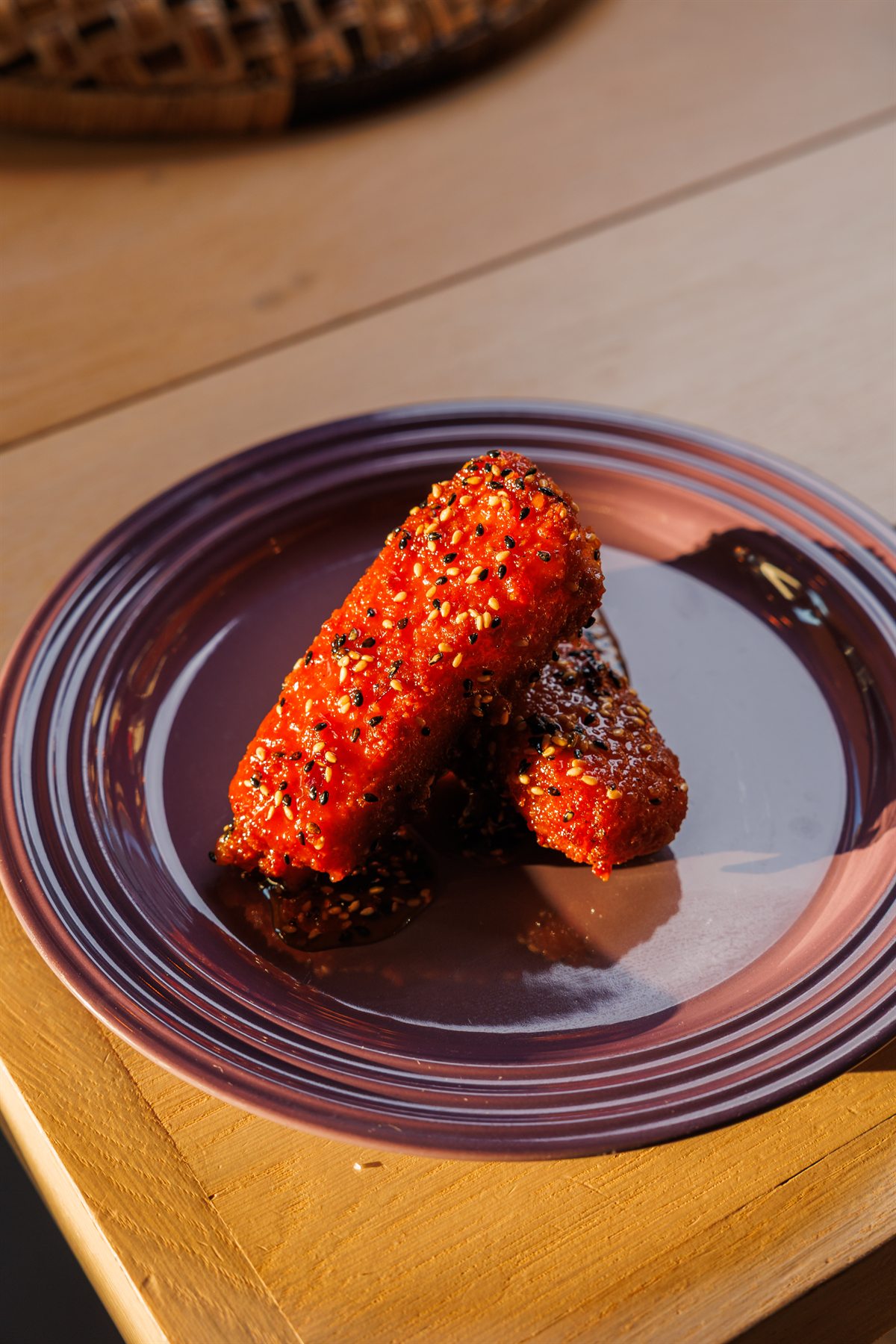 Crispy sesame-glazed mozzarella catching the light on a purple plate at Mina's Table